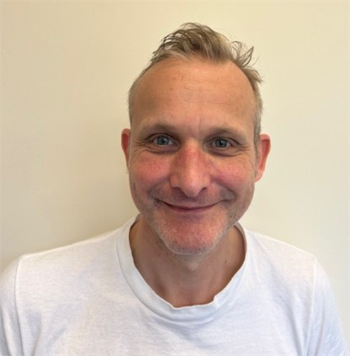 Photograph of a man with short blonde hair wearing a white t-shirt. Photograph of a man with short blonde hair wearing a white t-shirt.