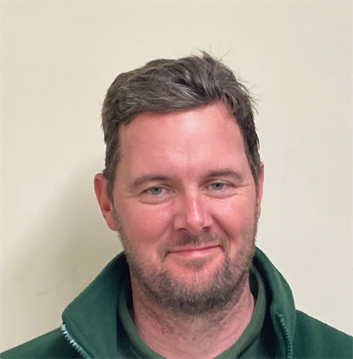 Photograph of a man with short, brown hair wearing a dark green polo-shirt and fleece. He is smiling. Photograph of a man with short, brown hair wearing a dark green polo-shirt and fleece. He is smiling.