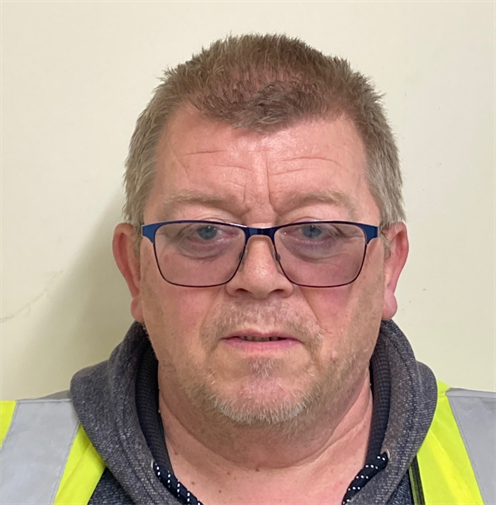 Photograph of a man with short blonde hair with glasses. He is wearing a grey hoodie under a high visibility vest. Photograph of a man with short blonde hair with glasses. He is wearing a grey hoodie under a high visibility vest.