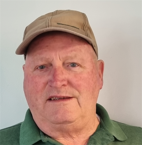 Photograph of a man with short hair, dark green polo shirt and jumper. He's wearing a beige hat. Photograph of a man with short hair, dark green polo shirt and jumper. He's wearing a beige hat.